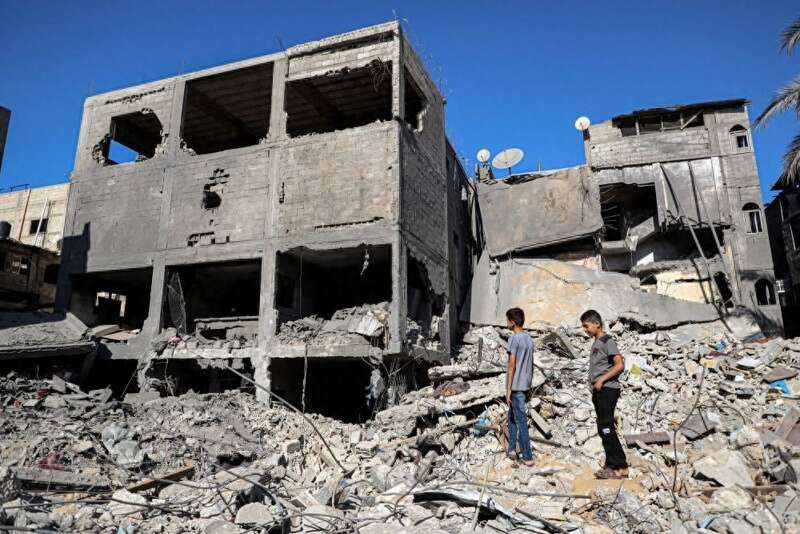 男孩站在遭以色列袭击损毁的建筑中